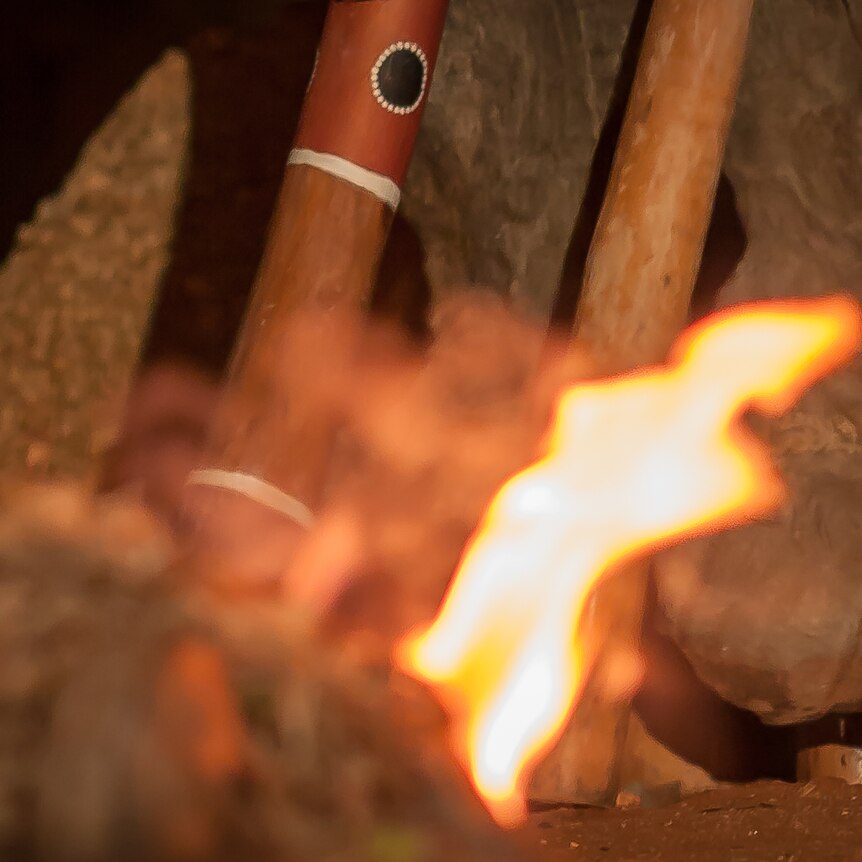 Aboriginal clapsticks from Central Australia sitting next to a campfire.