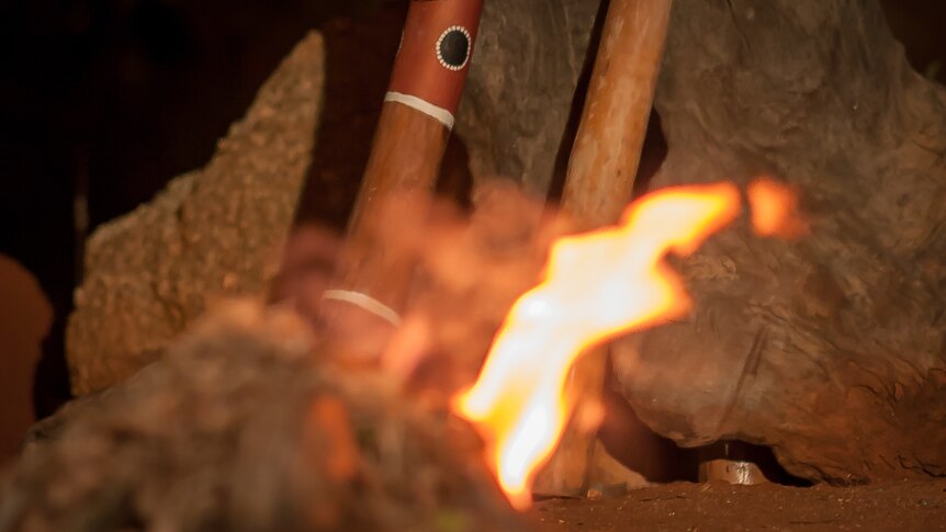 Aboriginal clapsticks from Central Australia sitting next to a campfire.