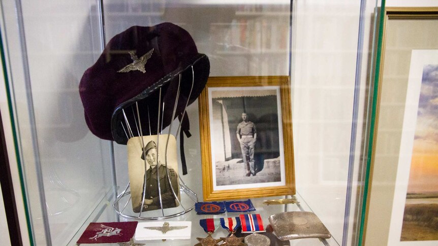 Photographs, a hat, medals and patches in a glass cabinet