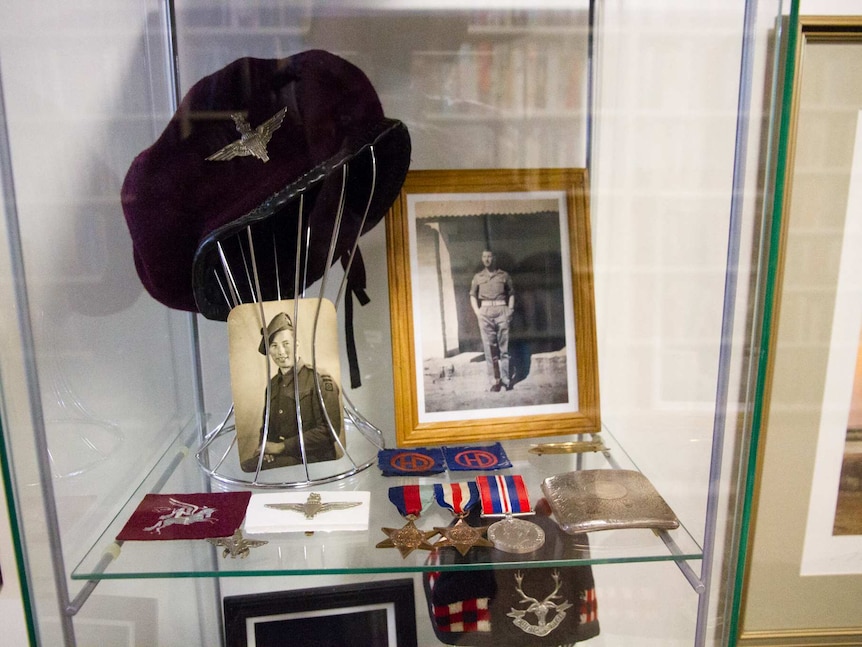 Photographs, a hat, medals and patches in a glass cabinet