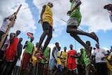 Two men jump in the air for a high jump competition.