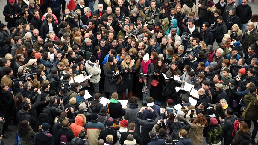 Members of the public sing following a remembrance rally at Place de la Republique