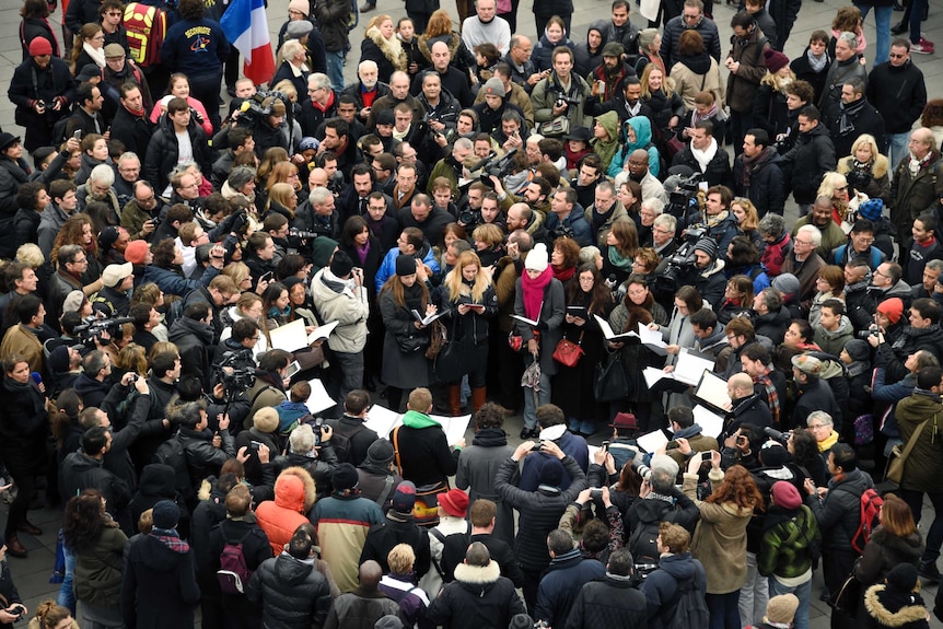 Members of the public sing following a remembrance rally at Place de la Republique