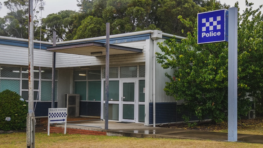 An police station with two signs. The building looks fairly old and is painted blue and white.