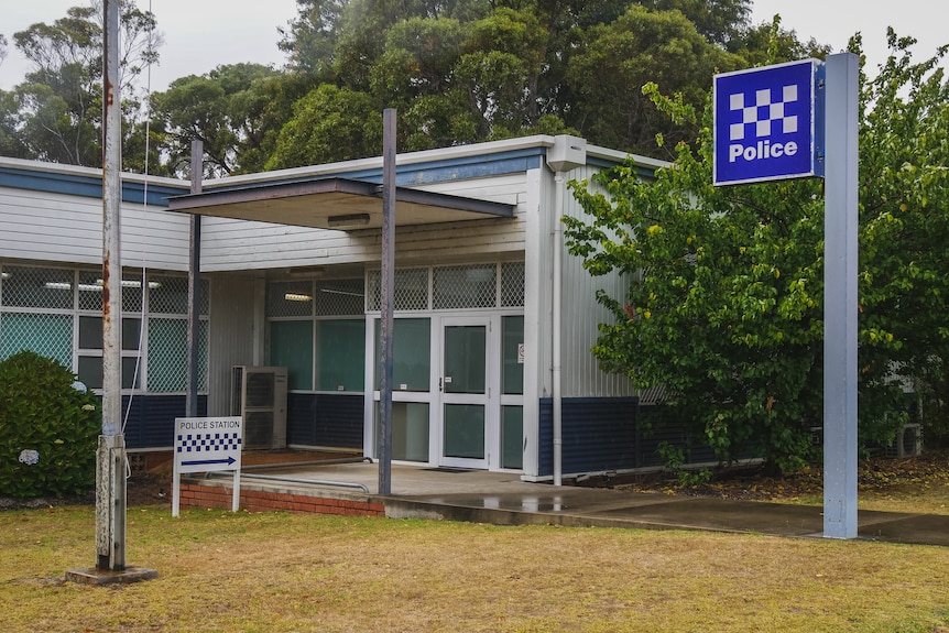 An police station with two signs. The building looks fairly old and is painted blue and white.