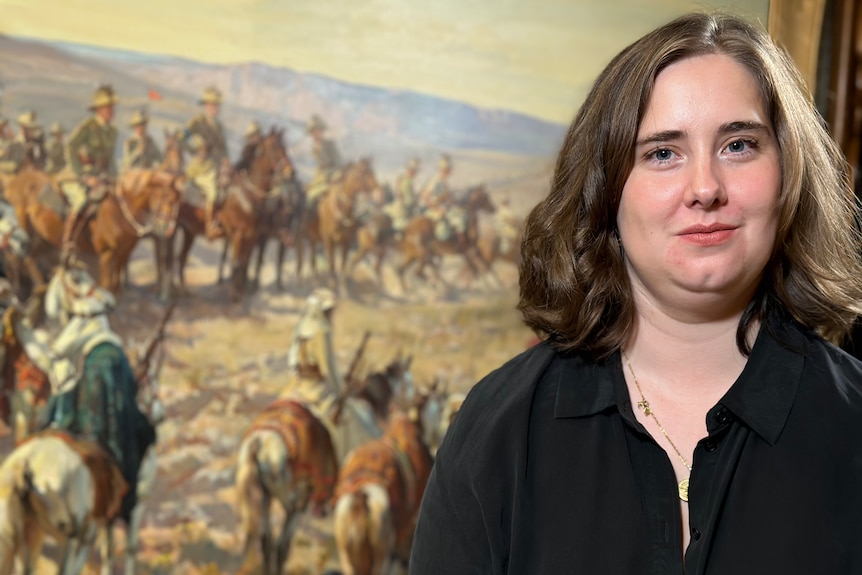 Photo of a woman standing in front of a painting.