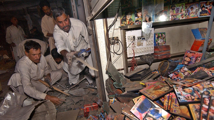 Pakistani bomb disposal squad members in a music shop in Peshawar, inspecting the site of a blast that wounded 17 people.