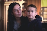 A woman with black hair sits next to a boy with brown hair.