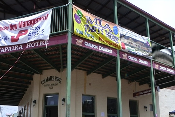 The outside of a country pub, with banners hanging from the top balcony