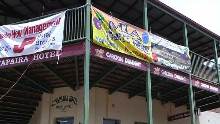 The outside of a country pub, with banners hanging from the top balcony