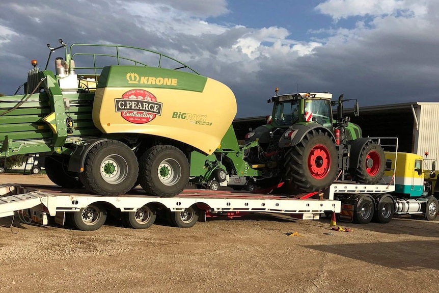 Tractor and baler on the back of a truck.