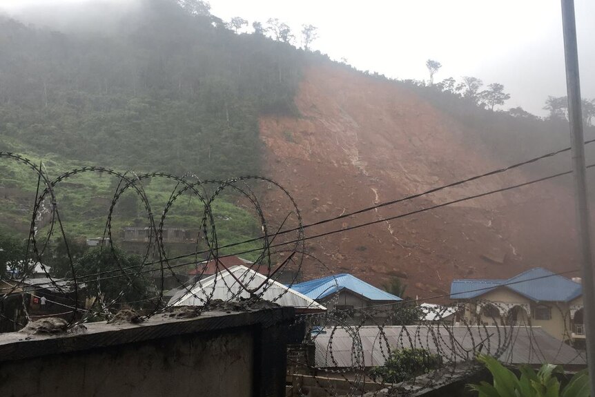 A wide section of hill, which sits behind homes, is covered with mud.