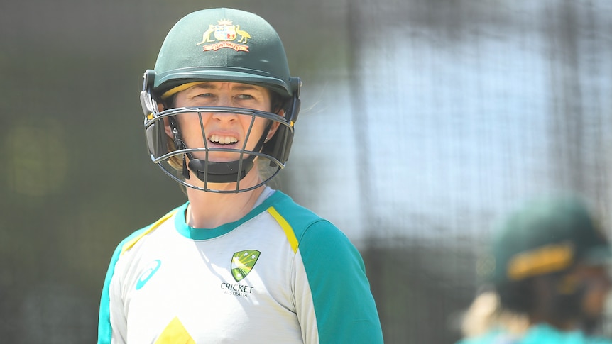 Female cricketer standing with her head gear on 