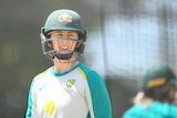 Female cricketer standing with her head gear on 
