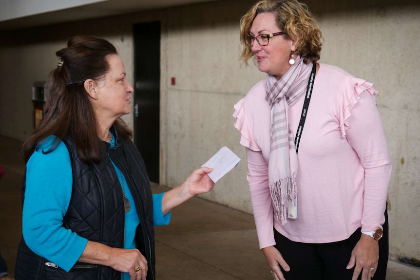 Lady handing an envelope of photos to another lady.