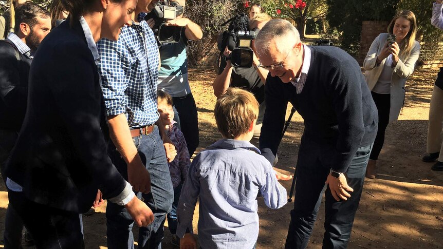 Six year old Harry Miles shakes Prime Minister Malcolm Turnbull's hand, as his parents and the media look on.