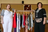 Photograph of two plus size women and a rack of clothing 