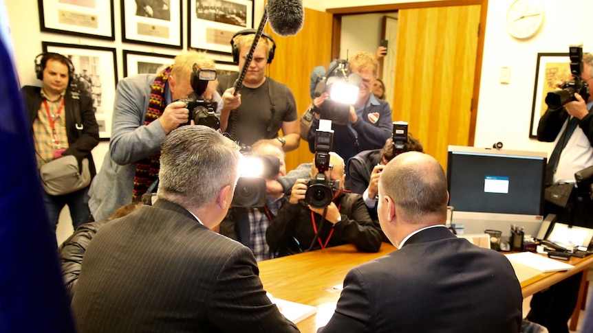 Josh Frydenberg and Mathias Cormann are seen from behind as media photograph them on Budget day.