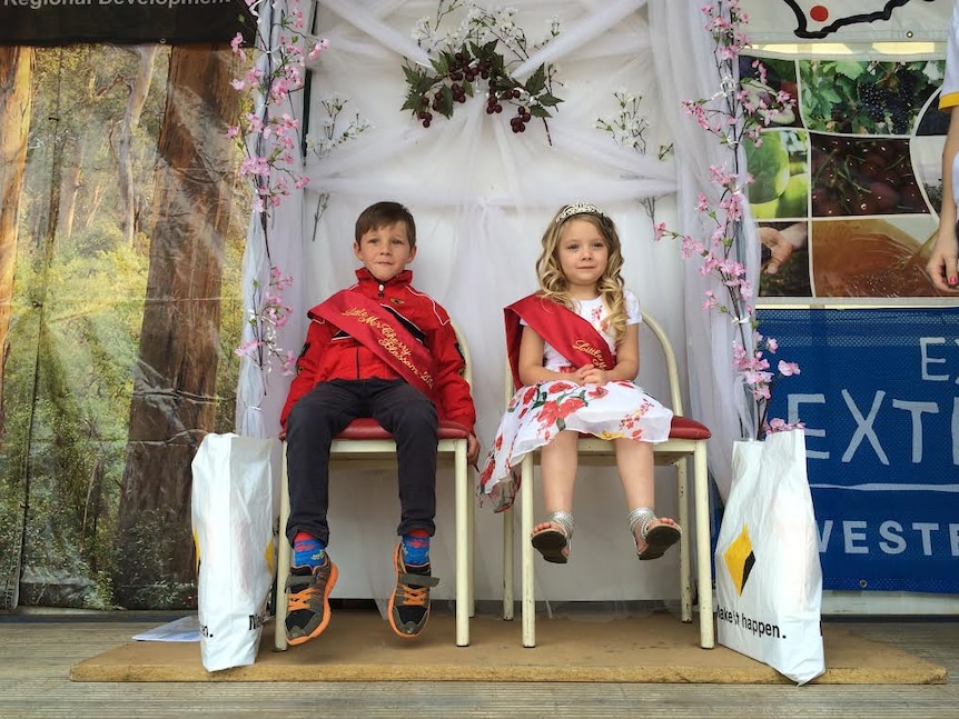 two happy children sitting on a large chair at a cherry festival