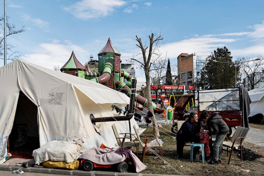 A white tent can be seen as well as a children's playground behind it. 