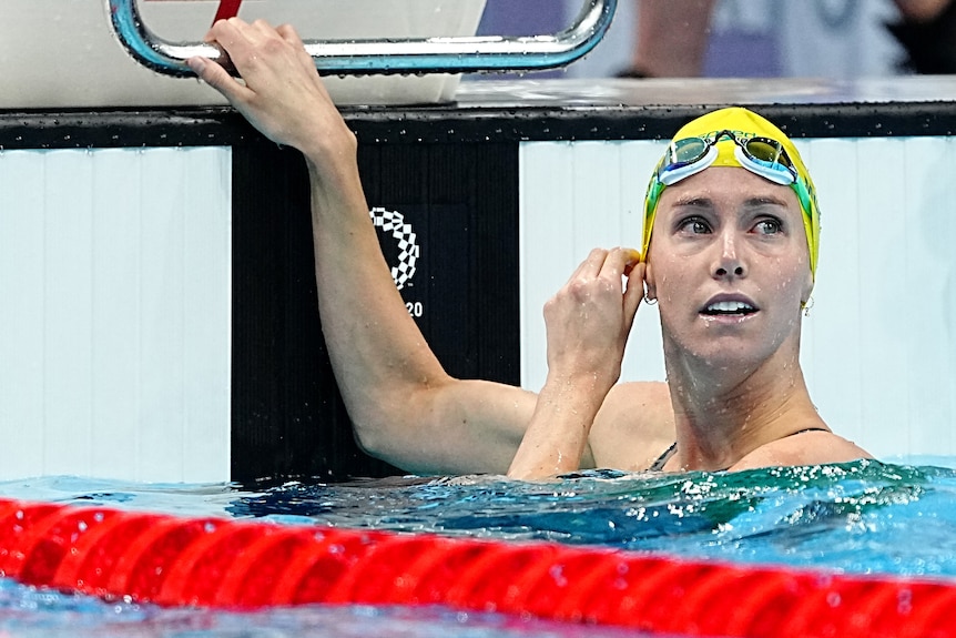 A woman wearing a yelloe swimming cap in the water