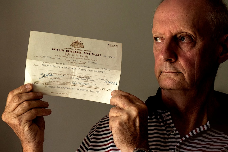A man hold a "Interim Discharge Certificate" from the Australian Defense Department.