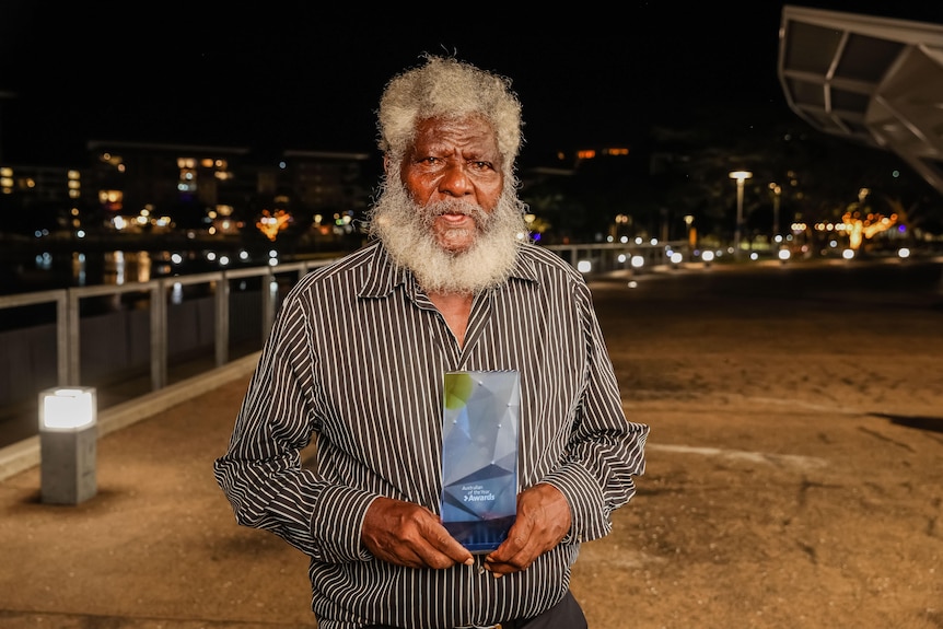 Man holding a trophy at night outside at Darwin Waterfront.