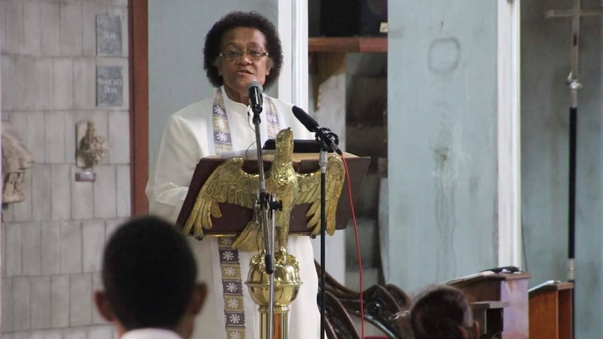 Reverend Sereima Lomaloma preaches at a lectern at the front of a church.