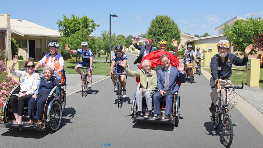 Elderly people smiling and waving on trishaws.