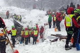 Rescuers work in the snow at the site of a hotel wrecked in an avalanche.
