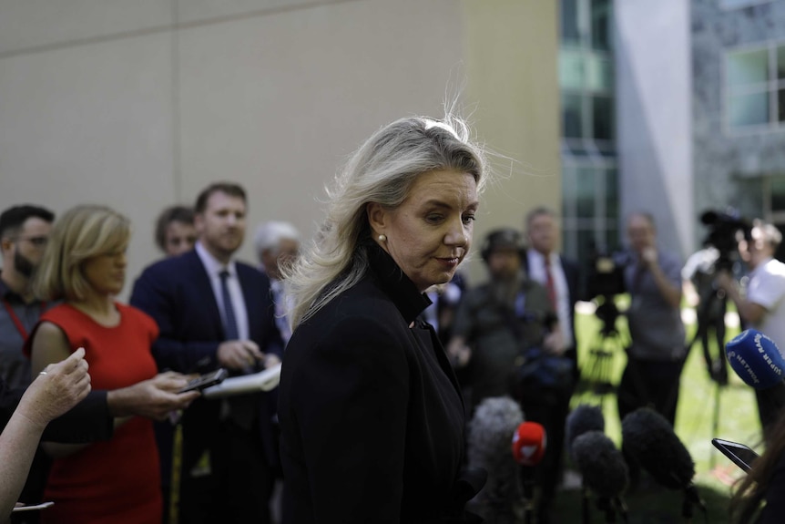 Bridget McKenzie looks to her right, surrounded by journalists and cameras in a courtyard