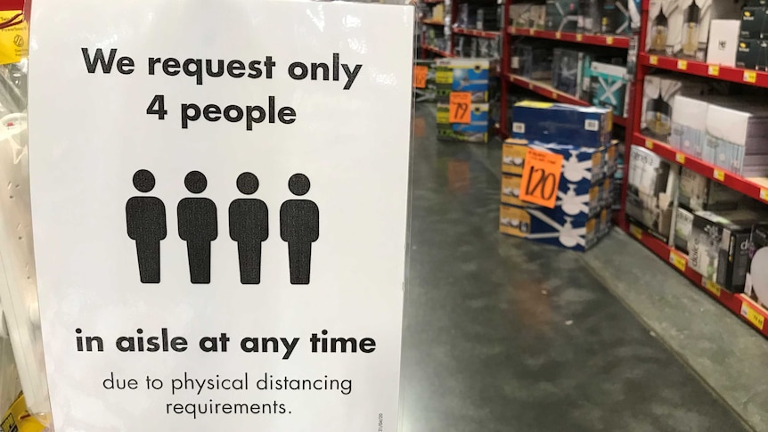 A sign in a Bunnings aisle during coronavirus restrictions reads 'We request only 4 people in aisle at any time'.