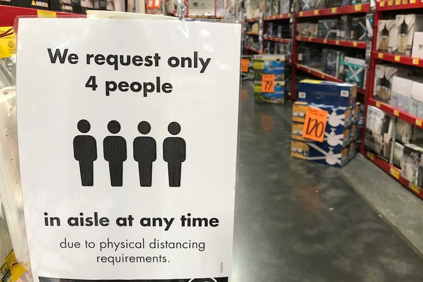A sign in a Bunnings aisle during coronavirus restrictions reads 'We request only 4 people in aisle at any time'.