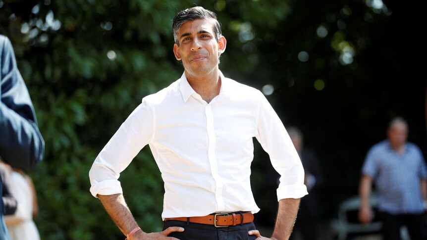 Rishi Sunak in a white shirt with his hands on his hips 