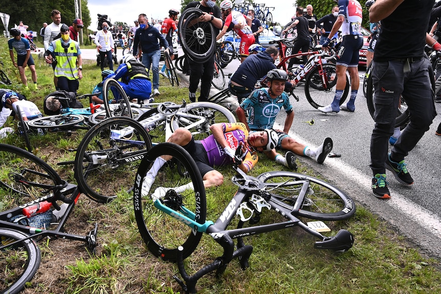 A mess of fallen cyclists, two being attended to by medical personnel