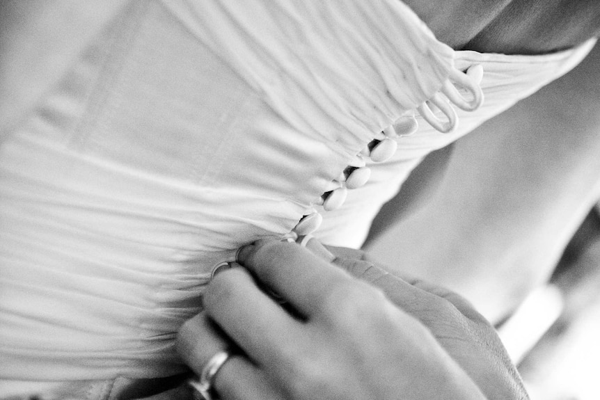 A close-up of a woman's hands working on a wedding dress