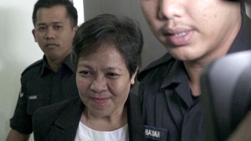 Maria Exposto seen with security staff at a Malaysian court.