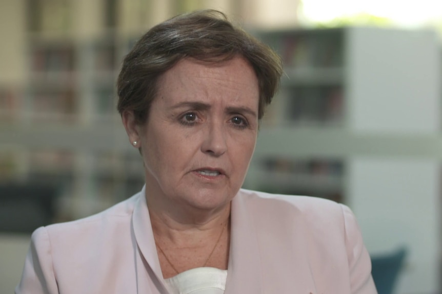 Female school prinicipal wearing light pink blazer speaking to an interviewer.