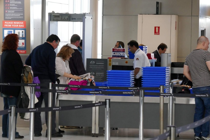 Travellers go through security at an airport.