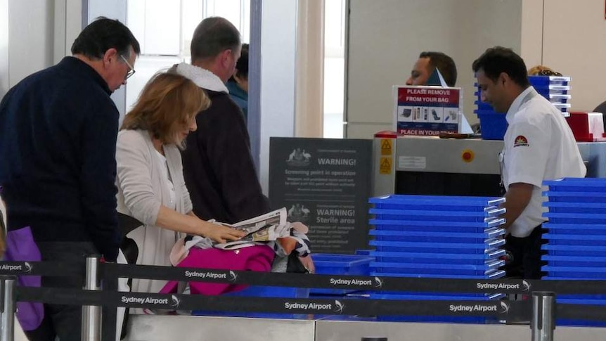 Travellers go through security at an airport.