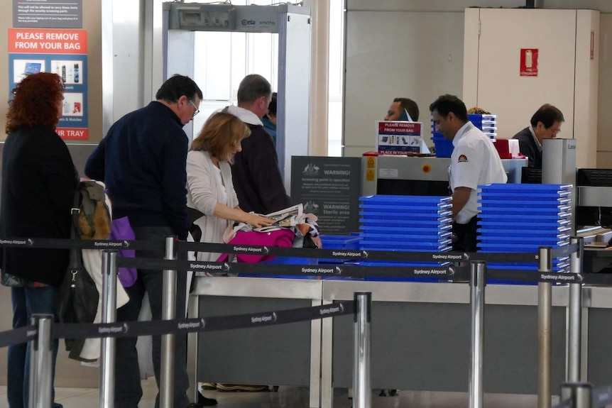 Travellers go through security at an airport.