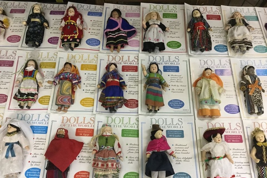 Three rows of dolls displayed on cards in world cultural dresses