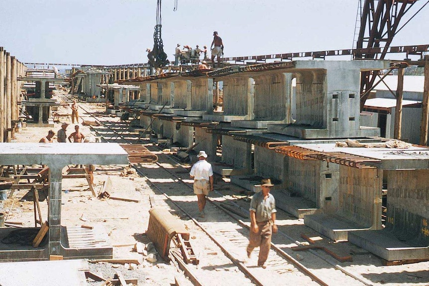 Men at work on the Narrows Bridge, surrounded by concrete sections.