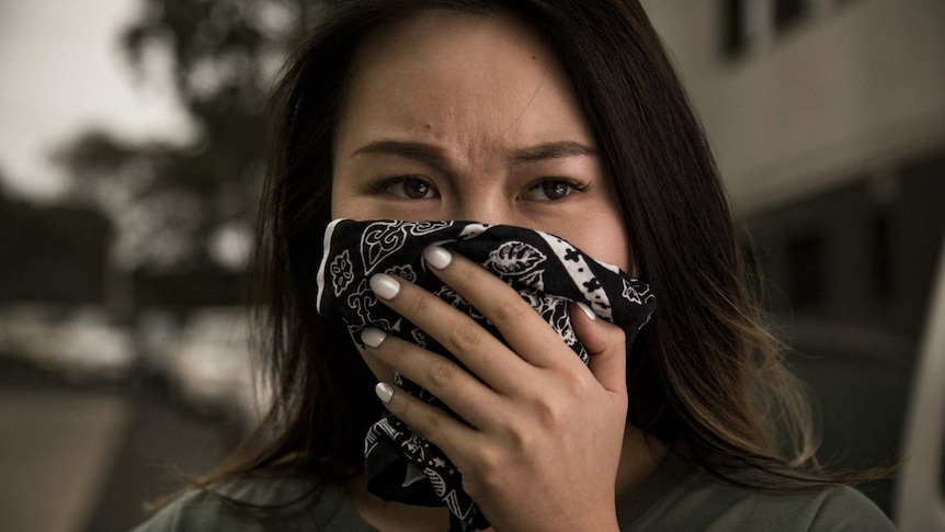 A woman covers her mouth with a handkerchief