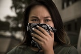 A woman covers her mouth with a handkerchief