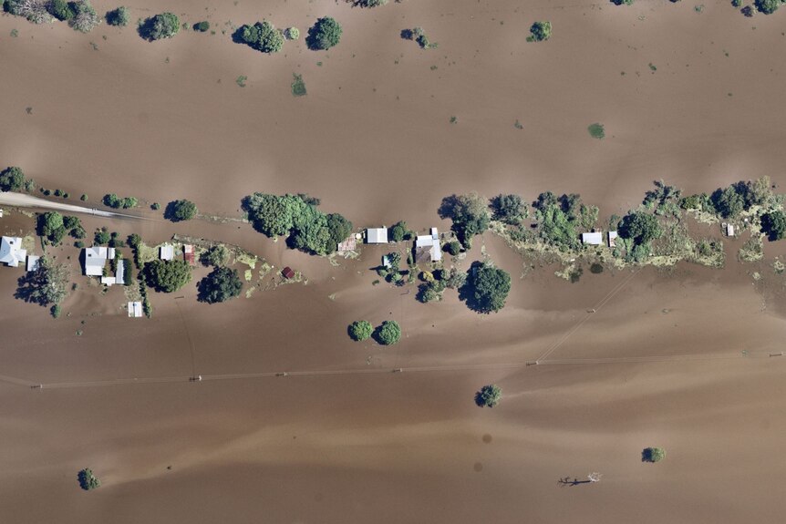 Two houses are seen from above, surrounded by floodwaters.