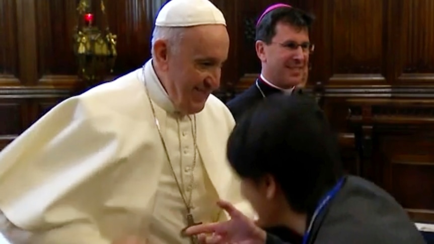 Pope Francis quickly pulls his hand back as a man who's leaning down tries to kiss the ring on his right hand