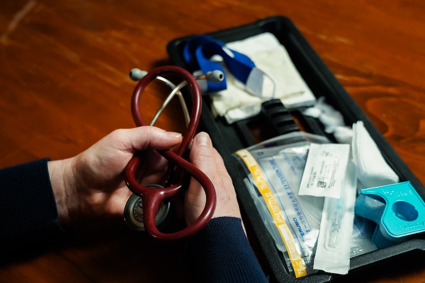 A small bag with medical equipment and a woman's hands holding a stethoscope.