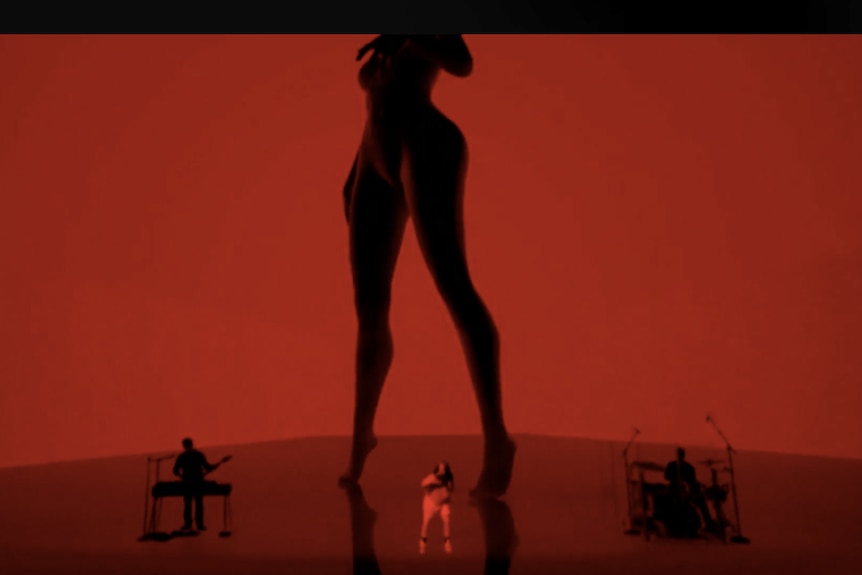 Screenshot of Billie Eilish performing 'bad guy'; silhouette of woman's body on screen in red and black