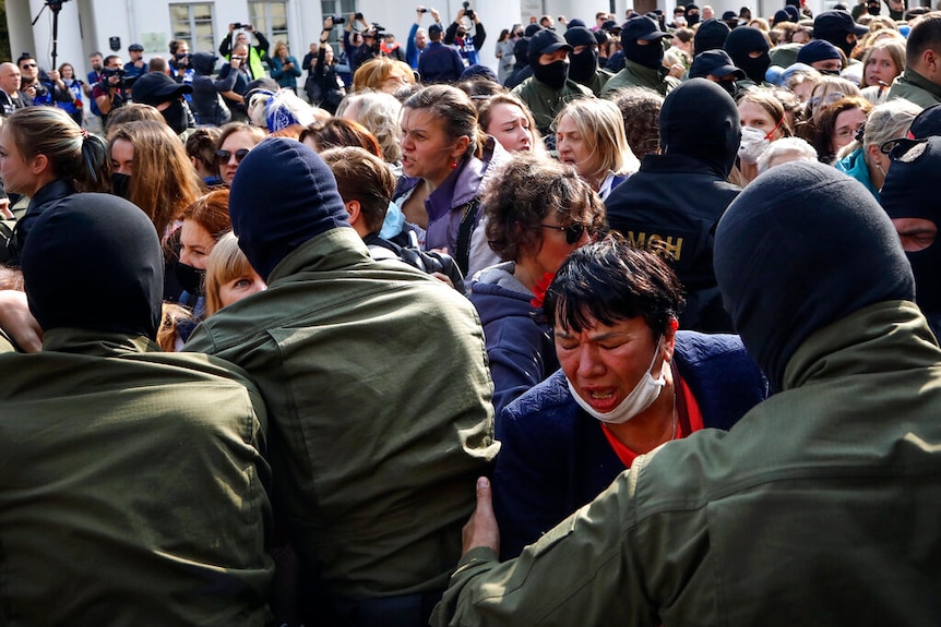 Women react, standing in front of police line during an opposition rally to protest the official presidential election results.